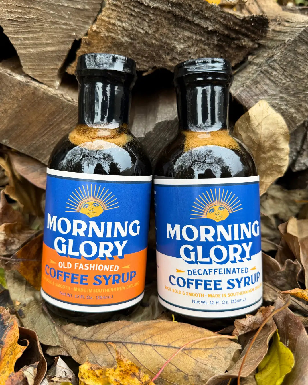 Morning Glory Old Fashioned and Decaffeinated Coffee Syrup Bottles on leaves and wood background.
