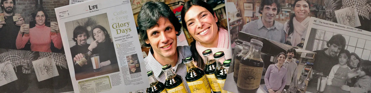 A collage-style promotional scene showing the owners in a home interior, newspaper clippings, framed photos, and multiple bottles of what appears to be beer or an alcoholic beverage arranged in the foreground.